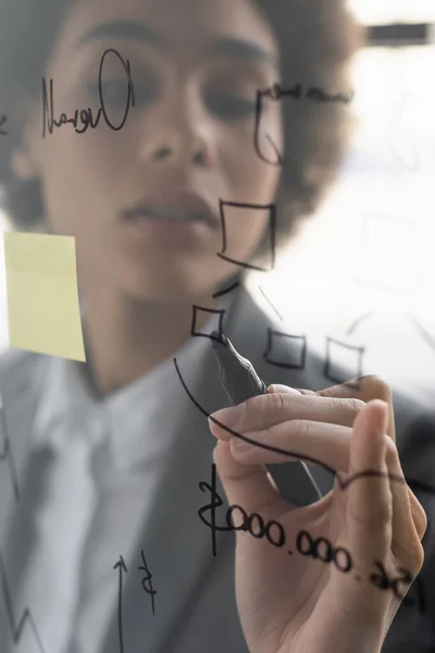 Marcador en mano de mujer de negocios afroamericana dibujando en tablero de vidrio - foto de stock