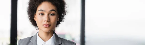 Joven mujer de negocios afroamericana mirando la cámara, pancarta - foto de stock