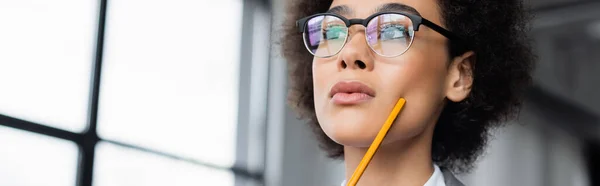 Vue en angle bas de femme d'affaires afro-américaine avec crayon regardant ailleurs, bannière — Photo de stock