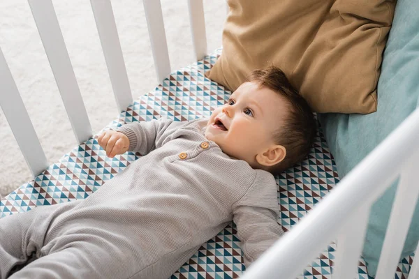 Blick aus der Vogelperspektive auf einen kleinen Jungen, der im Babybett liegt — Stockfoto