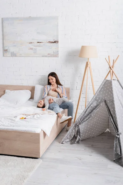 Fürsorgliche junge Mutter hält glückliches Baby im Bett — Stockfoto