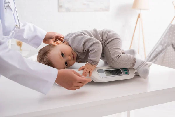 Pediatra afroamericano apoyando a niño infante a escala de bebé - foto de stock