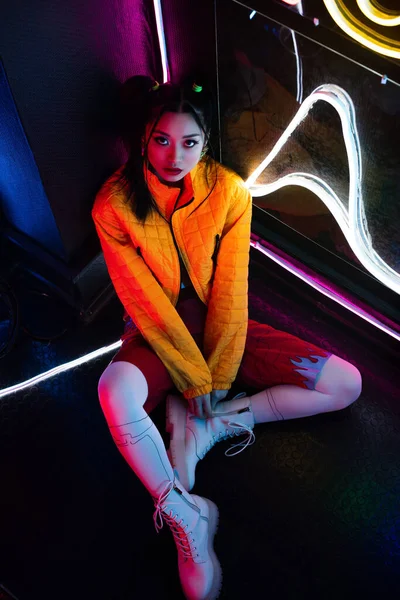 High angle view of young asian woman in bright clothing sitting on floor and looking at camera — Fotografia de Stock