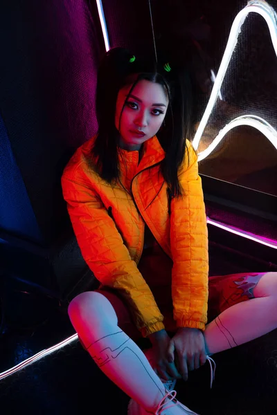 High angle view of young asian woman in bright clothing sitting on floor - foto de stock