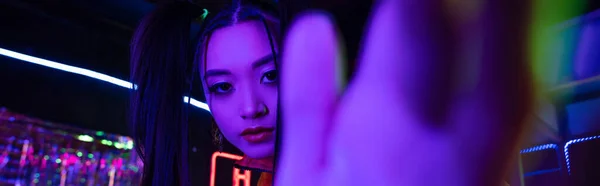 Young asian woman with blurred hand near neon sign, banner - foto de stock