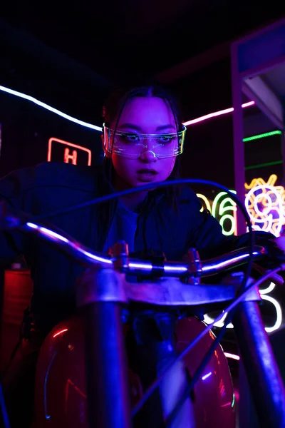 Young asian woman in sunglasses riding motorbike near neon sign — Photo de stock