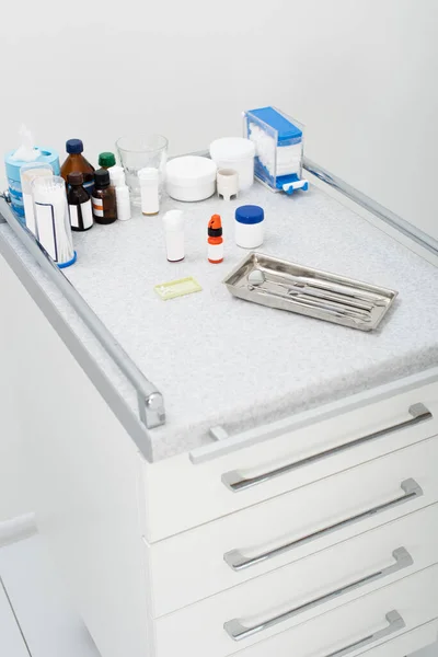Высокий угол обзора стоматологических инструментов в металлическом лотке и лекарственных препаратов на столе в клинике — стоковое фото
