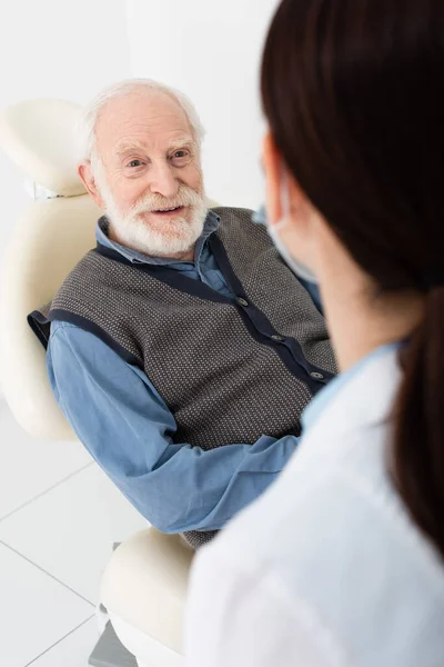 Paciente sénior en silla dental teniendo consulta con el médico en la clínica - foto de stock