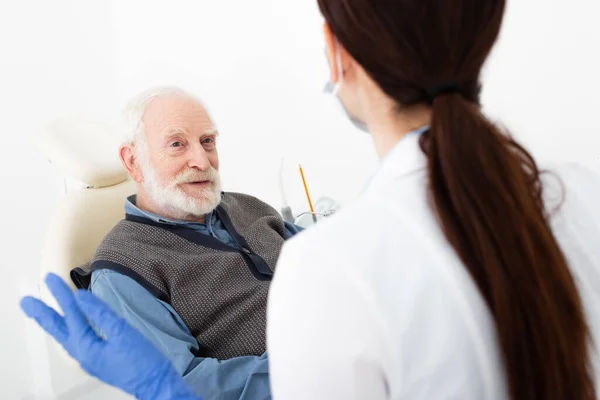 Patient âgé en fauteuil dentaire en consultation avec un médecin à la clinique — Photo de stock