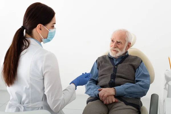 Patient âgé en fauteuil dentaire en consultation avec un dentiste en clinique — Photo de stock