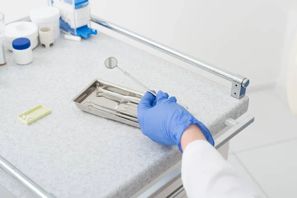 Ausgeschnittene Ansicht des Zahnarztes Hand in Latex-Handschuh Spiegel aus Metall Tablett auf Tisch in Zahnklinik — Stock Photo