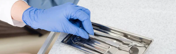 Close up tiro da mão dentista em luva de látex tomando ferramentas de bandeja de metal na mesa na clínica odontológica, banner — Fotografia de Stock