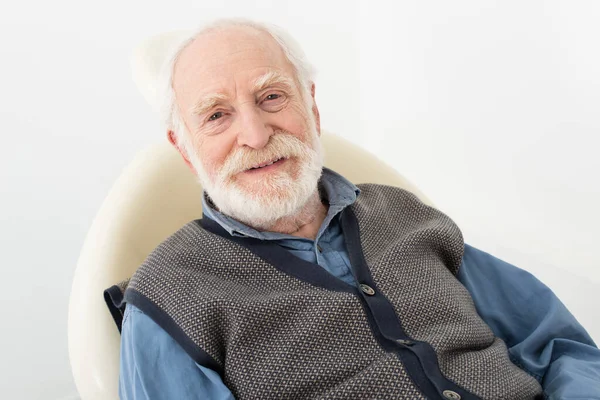 Smiling senior man sitting in dental chair and looking at camera isolated on grey — Stock Photo