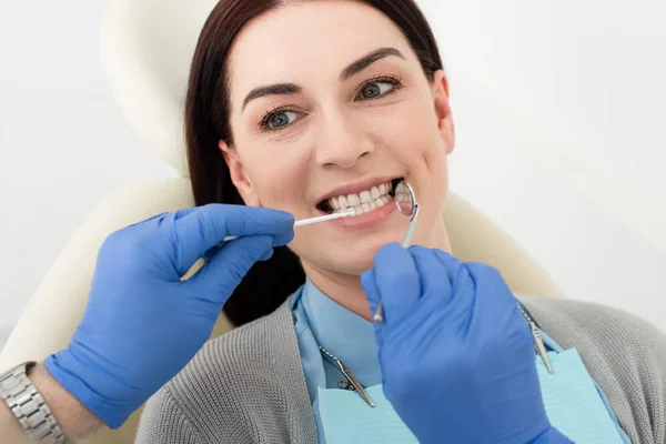 Dentista examinando dientes de mujer adulta con sonda y espejo en el hospital - foto de stock