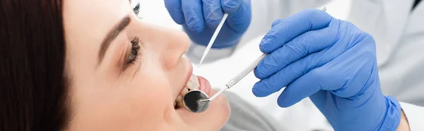 Nahaufnahme einer erwachsenen Frau bei der Untersuchung der Zähne durch den Arzt in Latexhandschuhen in der Klinik, Banner — Stockfoto