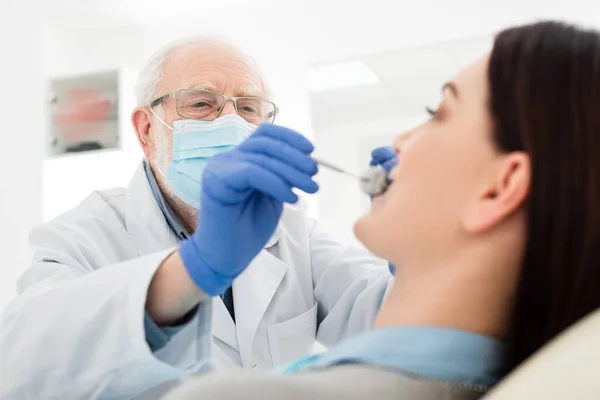 Dentiste chevronné faisant l'examen des dents de la femme en fauteuil dentaire — Photo de stock