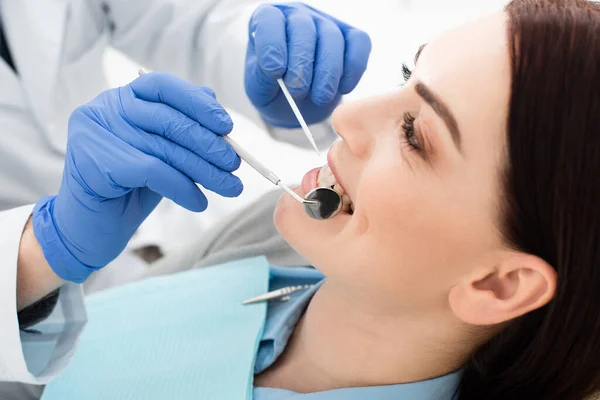 Visão de perto da mulher adulta que tem exame dos dentes pelo médico em luvas de látex na clínica — Fotografia de Stock