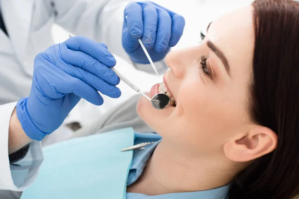 Vista da vicino di una donna adulta sottoposta a esame dei denti da parte del medico in guanti di lattice in clinica — Foto stock