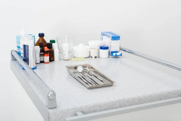 Medicamentos y herramientas de metal dental limpias en bandeja en la mesa médica - foto de stock
