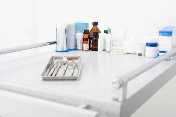 Medicines and clean dental metal tools in tray on medical table — Stock Photo