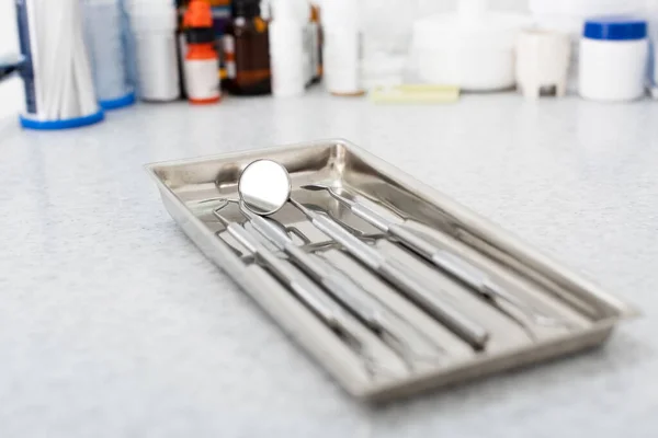 Крупним планом металеві зубні інструменти в лотку на медичному столі — стокове фото