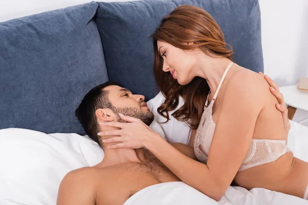 Vue latérale de la femme sensuelle touchant homme barbu sur le lit — Photo de stock