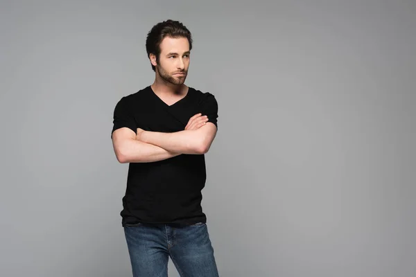 Hombre barbudo en camiseta negra posando con brazos cruzados aislados en gris - foto de stock