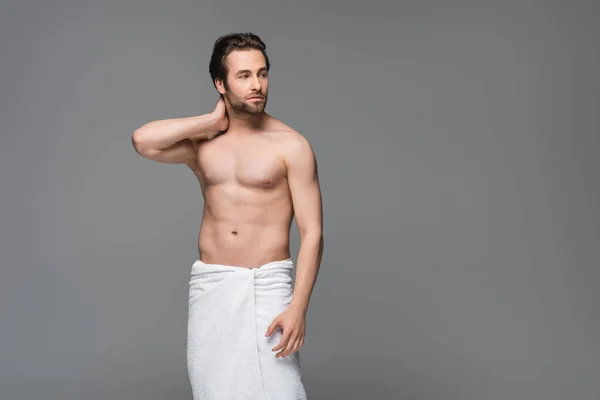 Uomo senza camicia avvolto in asciugamano in piedi isolato su grigio — Foto stock