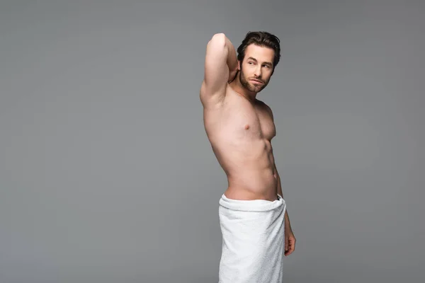 Muscular man wrapped in towel posing isolated on grey — Stock Photo