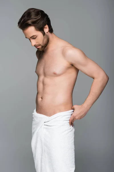 Молодий мускулистий чоловік регулює білий рушник ізольовано на сірому — стокове фото