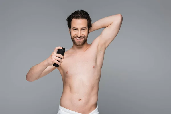 Uomo gioioso e senza camicia che tiene deodorante isolato su grigio — Foto stock