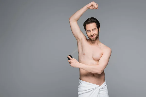 Uomo felice e senza camicia con mano sollevata utilizzando antitraspirante isolato su grigio — Foto stock
