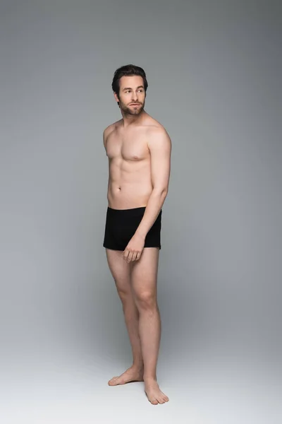 Comprimento total do homem sem camisa em roupa interior preta posando em cinza — Fotografia de Stock