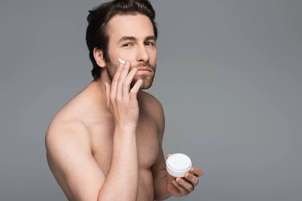 Shirtless man applying face cream isolated on grey — Stock Photo
