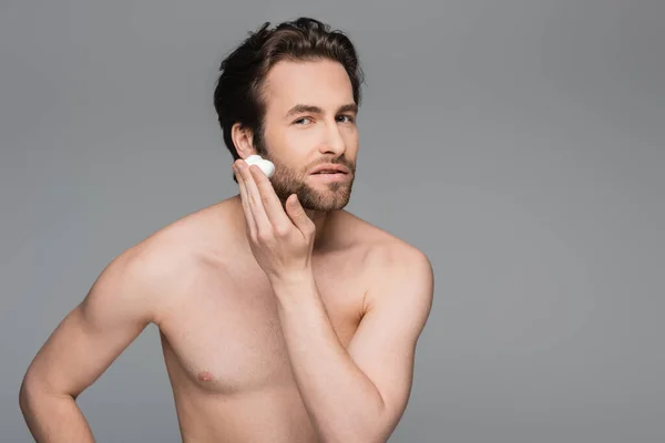 Без сорочки чоловік наносить піну для гоління на обличчя ізольовано на сірому — стокове фото
