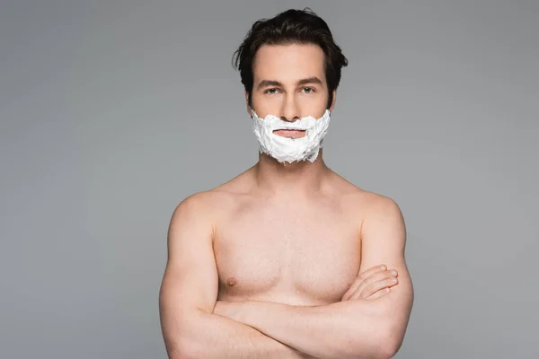 Jeune homme torse nu avec mousse à raser du visage posant avec les bras croisés isolés sur gris — Photo de stock