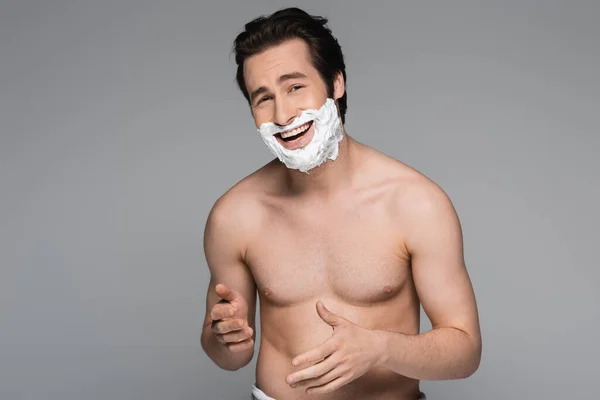 Happy and shirtless man with shaving foam of face laughing isolated on grey — Stock Photo