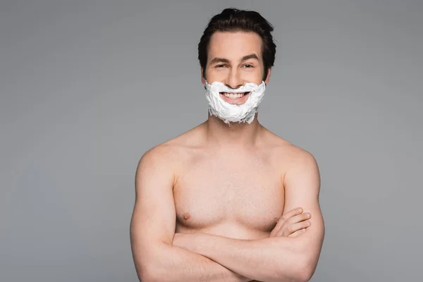 Homme heureux et torse nu avec mousse à raser du visage posant avec les bras croisés isolés sur gris — Photo de stock