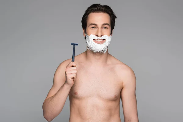 Shirtless man with foam on face holding safety razor isolated on grey — Stock Photo