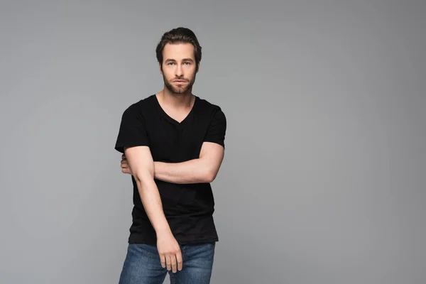 Bearded man in black t-shirt and jeans posing isolated on grey — Stock Photo