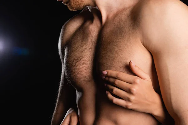 Partial view of female hands touching man with shirtless torso on black background — Stock Photo