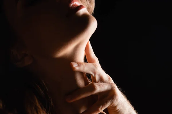 Vista de cerca de mano masculina tocando cuello de mujer aislado en negro - foto de stock