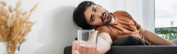 Hombre alcanzando un vaso de agua mientras sufre de calor, bandera - foto de stock