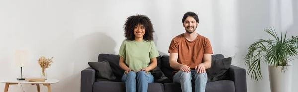 Happy multiethnic sitting on sofa in modern living room, hvac concept, banner — Stock Photo