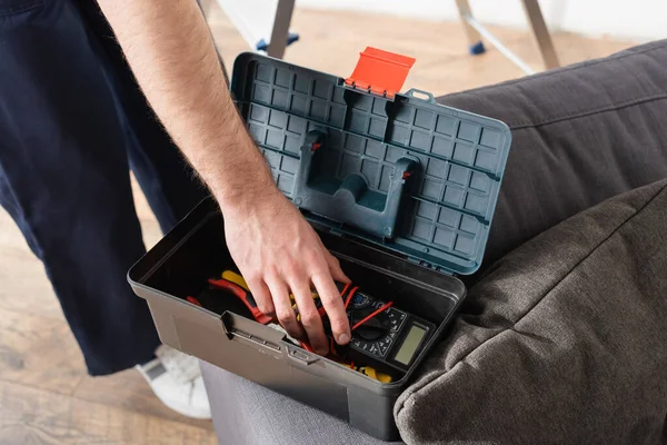 Vue recadrée de bricoleur prenant multimètre numérique de la boîte à outils — Photo de stock