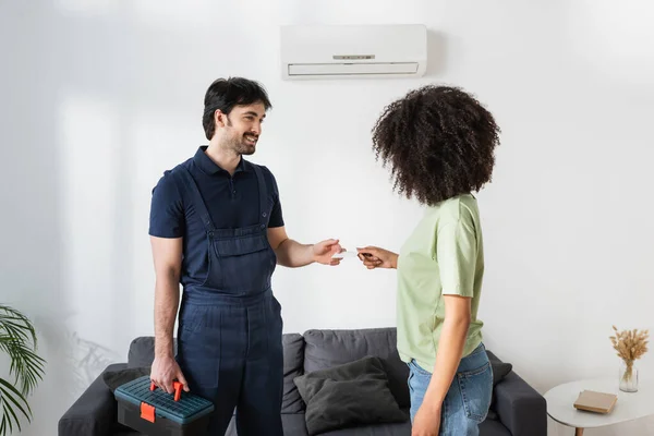 Happy handyman giving blank card to curly african american woman — Stock Photo