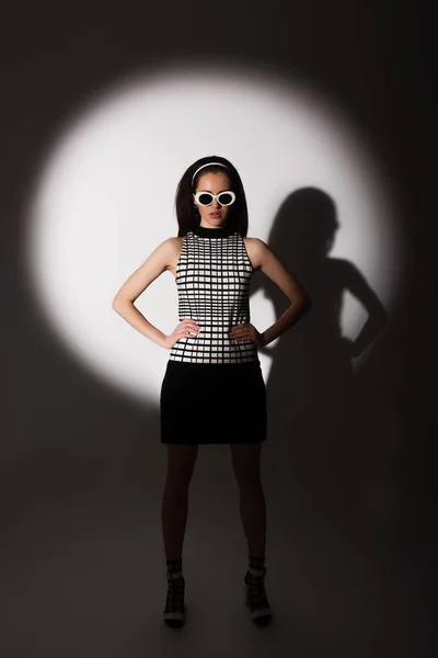 Full length of lighting on trendy model in sunglasses posing with hands on hips on grey — Stock Photo