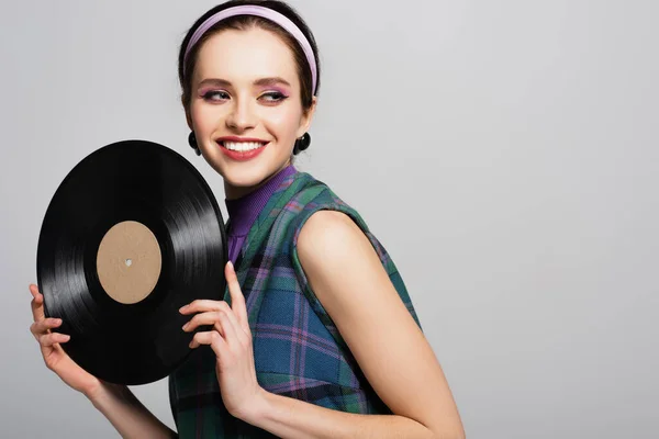 Mulher alegre na cabeça segurando disco de vinil retro isolado em cinza — Fotografia de Stock