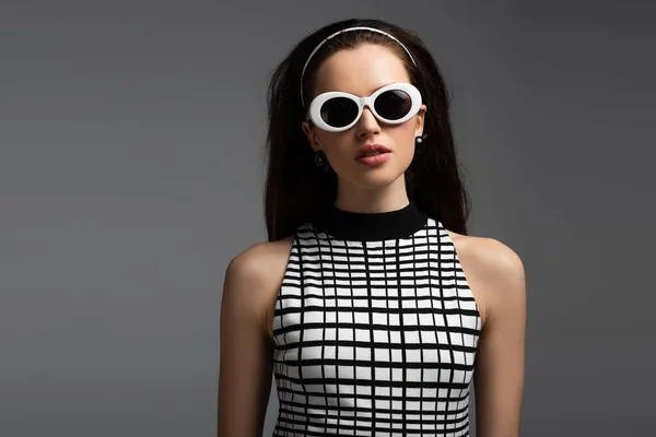 Junge brünette Frau mit Stirnband, Retro-Frisur und Sonnenbrille isoliert auf grau — Stockfoto