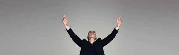 Homem de meia idade em óculos e terno apontando com os dedos em cinza, banner — Fotografia de Stock